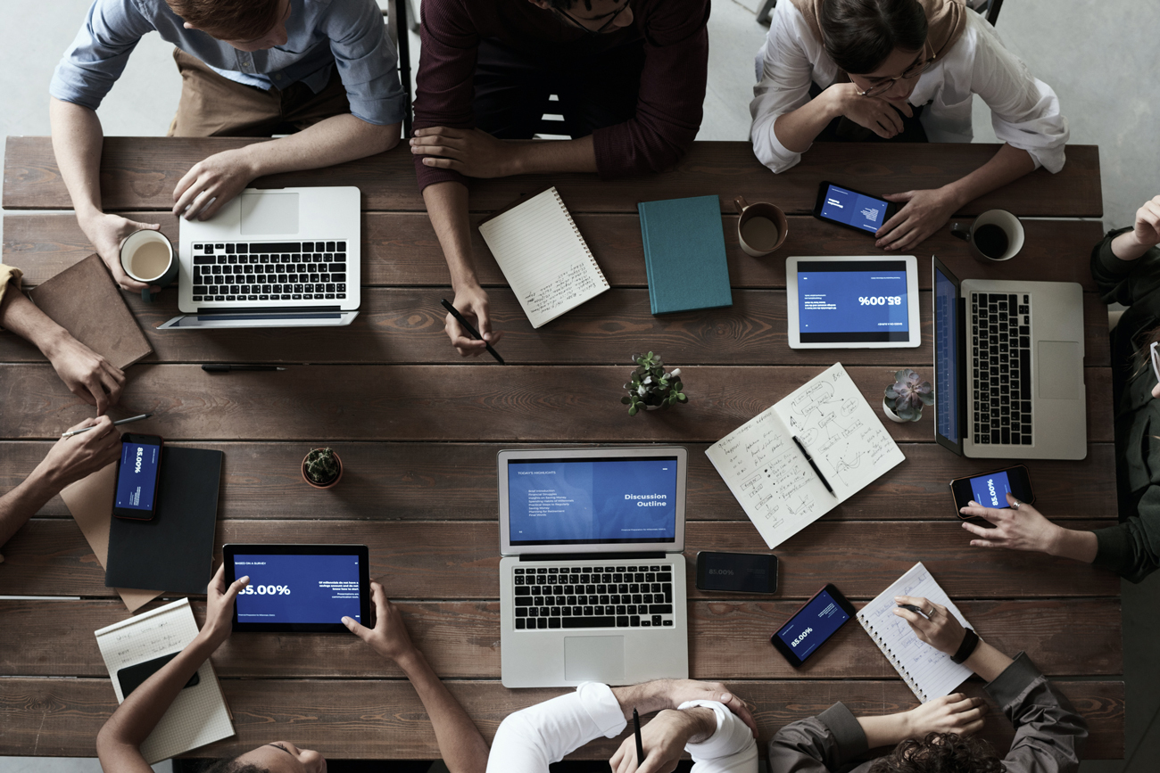 A team sit together at a meeting using electronic devices